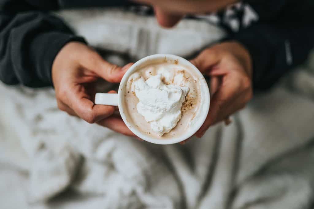 Does Hot Chocolate Have Caffeine- person drinking hot chocolate in bed